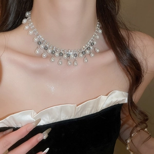 Gros plan d'un collier argenté orné de perles blanches et grises et de strass brillants