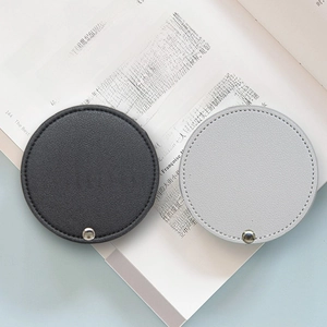 Portable PU leather mini makeup mirrors in black and light gray on an open book