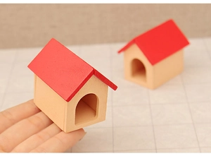 Close-up of hand holding a miniature wooden Christmas house with red roof decor