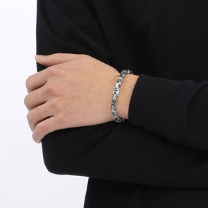 Close-up of a silver stainless steel square link bracelet worn on a person's wrist