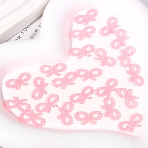 Close-up of pink ABS imitation pearl bow charms for DIY phone case crafts on a heart tray