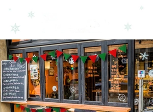 Close-up of red and green felt pennant banner hanging in a cozy cafe window for Christmas