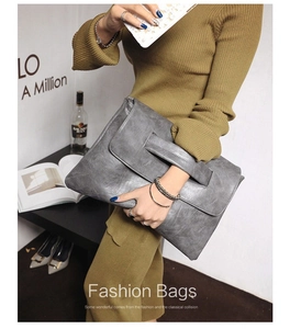 Detail of grey PU leather clutch bag featuring wide handle and vintage texture