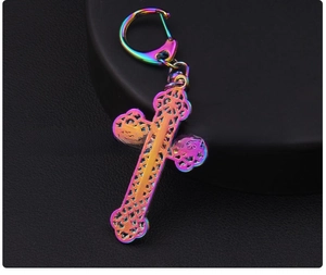 Close-up of the back side of a hollow colorful alloy cross keychain with rainbow plating