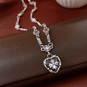 Macro shot of vintage gothic cross heart pendant with red gems and ornate silver carving