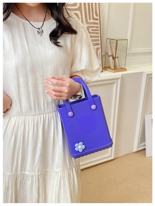 Detail der lila EVA-Tasche mit blauer Blumen-Applikation an Modell in weißem Kleid