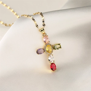 Detailed macro view of colorful zircon cross pendant on gold chain necklace