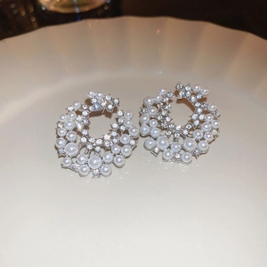 Detailed view of silver flower earrings with pearls and crystals on a ceramic tray