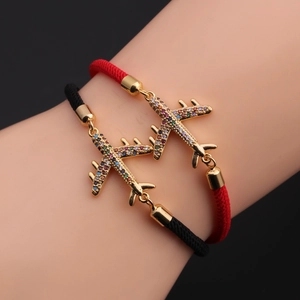 Close-up of woven couple bracelets with colorful zircon airplane charms on wrist