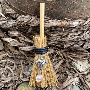 Mini witch broom charm with silver turtle and rose quartz over natural bark background