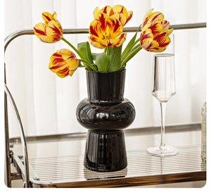 Detail of elegant black ribbed glass vase with fresh tulips on a stylish metal trolley