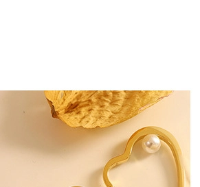 Close-up of gold plated heart ring with inlaid white shell pearl on a warm background