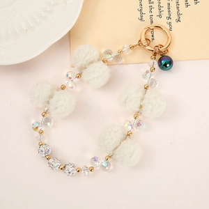 Detail of white pompom beads and iridescent crystals on a gold chain keychain