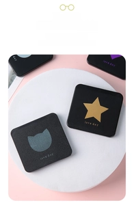 Detail of portable black matte makeup mirror with gold star and cat head patterns