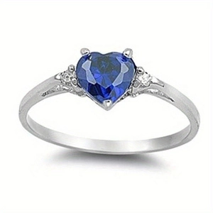 Detailed close-up of a silver heart ring featuring a large deep blue sapphire gemstone