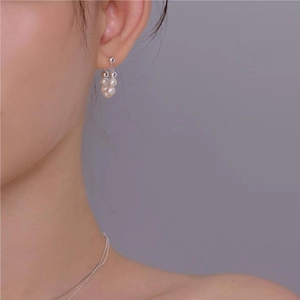 Close-up of elegant pearl drop earrings worn by a model in a minimalist style