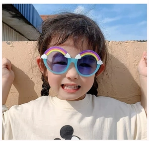 Outdoor shot of a child wearing light blue rainbow round sunglasses with purple lenses
