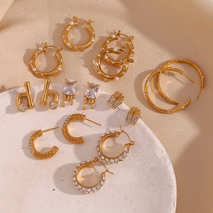 Close-up of 18K gold plated earrings featuring pearl and zircon inlay on silk texture