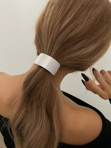 Detail of white glitter geometric ponytail cuff with matte finish on blonde hair