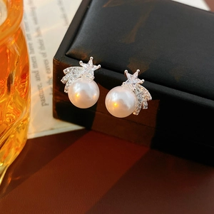 Détail macro de boucles d'oreilles perles et étoiles avec zircons sur un coffret