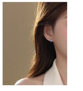 Close-up of a model wearing the minimalist blue zircon stud earring on the ear lobe