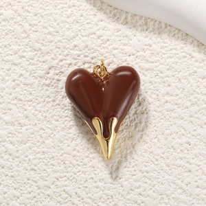 Macro detail of a heart pendant featuring dark brown enamel and gold plated metal finish