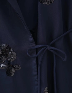 Detailansicht aus dunkelblauem Satin mit schwarzen Paillettenstickereien und Taillenband