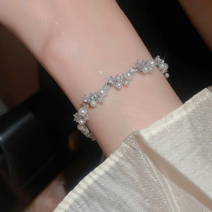 Detailed view of silver zircon and pearl wrap bracelet worn on a woman wrist