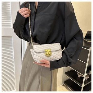 Detail of white quilted crossbody bag with golden chain strap and metallic lock closure