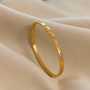 Elegant gold titanium steel bangle featuring six square-set zircons on satin background
