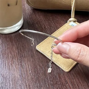 Detail of a minimalist silver S925 bangle with a fine chain and rectangle charm pendant
