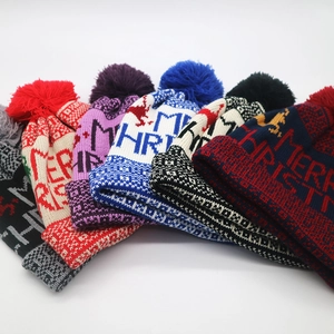 Close-up of Merry Christmas jacquard knit beanies with fluffy pom poms and winter patterns
