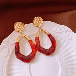 Macro detail of vintage gold textured earrings with amber oval resin drops on ceramic