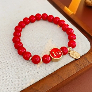 Vue détaillée d'un bracelet en perles rouges avec des breloques dorées Fu sur un plateau