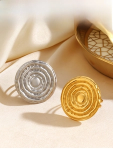 Close-up of geometric wave textured rings in gold and silver finish on silk fabric