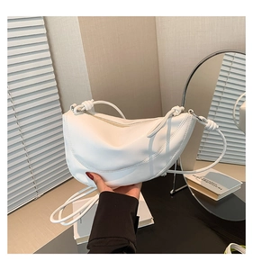 Detailed view of white leather half-moon shoulder bag with unique knotted strap detail