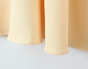 Détail de l'ourlet de la robe jaune clair montrant les coutures et la texture du tissu