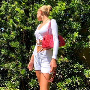 Side view of white lace-up crop top and shorts set with a red faux crocodile handbag