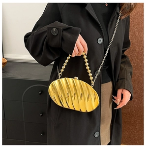 Detailed view of golden leaf-shaped acrylic evening bag with beaded handle and metal chain