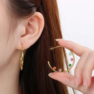 Detail of C-shaped gold stainless steel earrings with colorful round zirconia stones