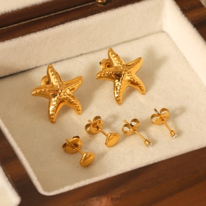 Ensemble de boucles d'oreilles étoile de mer et coquillage dorés dans une boîte en bois