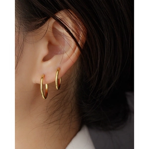 Close-up of elegant gold s925 silver hoop earrings worn in a stylish layered fashion
