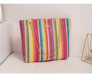 Detailed view of rainbow striped woven tote bag with gold chain straps and metal plaque