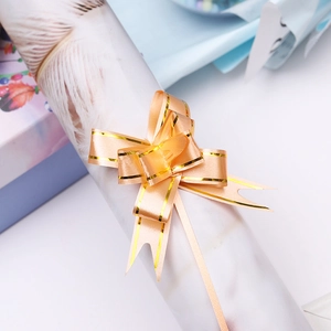 Close-up of champagne gold gift ribbon bow with gold trim on festive packaging paper