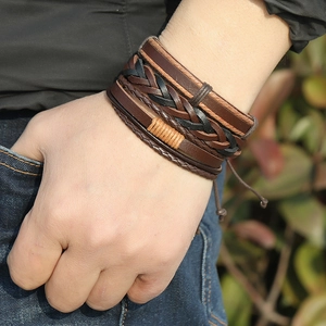 Detail shot of multi-layer brown braided leather bracelets on wrist in casual setting