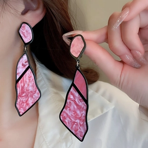 Detail of large geometric pink marble acetate drop earrings with black frames on ear