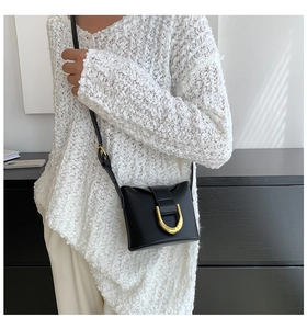 Detail of elegant black shoulder bag featuring a signature golden D-shaped metal buckle