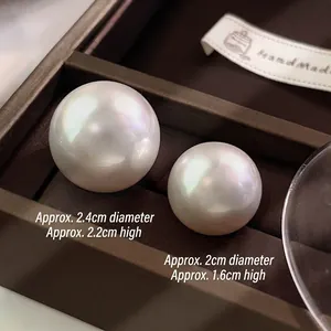 Chic oversized round white pearl earrings in two sizes displayed on brown jewelry box