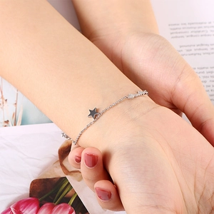 Fashionable silver star charm bracelet with letter engraving shown on a female wrist