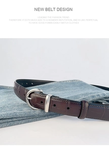 Detail of dark brown crocodile texture leather belt with silver horseshoe buckle on jeans